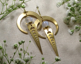 May include: Gold crescent moon earrings with a moon phase design and a white moonstone bead.