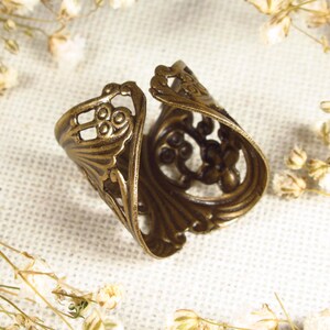 Puede incluir: Un anillo de metal dorado con un dise&ntilde;o intrincado y ornamentado. El anillo est&aacute; abierto y tiene un delicado patr&oacute;n de filigrana.