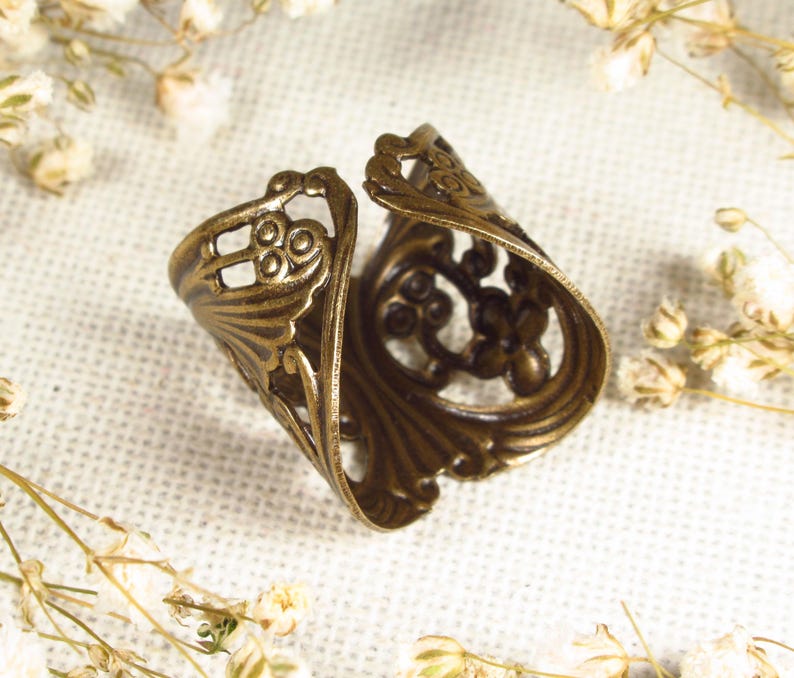 Puede incluir: Un anillo de metal dorado con un dise&ntilde;o intrincado y ornamentado. El anillo est&aacute; abierto y tiene un delicado patr&oacute;n de filigrana.