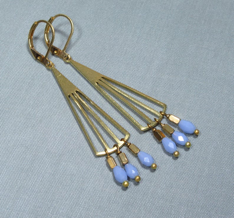 May include: Gold earrings with a geometric design and light blue glass beads.