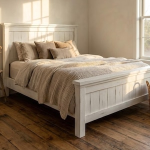Puede incluir: Una cama de madera blanca con cabecero a juego, vestida con ropa de cama de tonos neutros y una manta de punto grueso. La habitación cuenta con suelo de madera, una pequeña mesa auxiliar con un jarrón de flores secas y una cesta de mimbre.