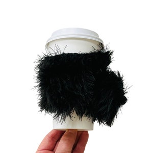 May include: A black, fuzzy Portuguese Water Dog coffee cup sleeve.  Fits snuggly around a 16oz coffee cup.