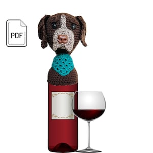 May include: A bottle of red wine with a decorative, crocheted dog head bottle stopper. The dog is brown with a white muzzle and a teal collar. A wine glass with red wine sits next to the bottle. A PDF icon is in the upper left corner.