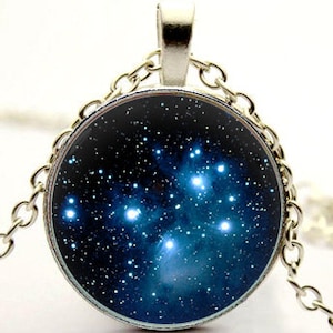 May include: A silver chain necklace with a round pendant featuring a blue galaxy with white stars.