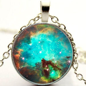 May include: A silver chain necklace with a round pendant featuring a colorful nebula image. The pendant has a silver rim and the nebula is a mix of blue, green, orange, and brown.
