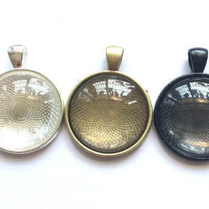 May include: Three round glass pendant trays with silver, gold, and black metal frames. The glass is clear and has a textured pattern.