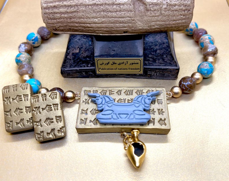 May include: A necklace with a pendant featuring a blue bull design and a small gold-colored amphora. The necklace has a beaded strand with blue, brown, and gold beads. Two rectangular pendants with ancient writing are also included.