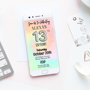 May include: A digital invitation on a smartphone screen for Alexa's 13th birthday party. The invitation has a rainbow watercolor background with a silver number 13 balloon. The text reads "Join Us In Celebrating Alexa's 13th Birthday, Saturday October 20th, 1216 Shine Avenue Mount Pleasant PA, RSVP, Scan by 10/15 at 555-456-7890."