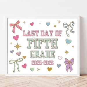 May include: A framed print with the text "LAST DAY OF FIFTH GRADE 2025-2026". The design includes pink and blue bows, hearts, and stars on a white background. The frame is white.