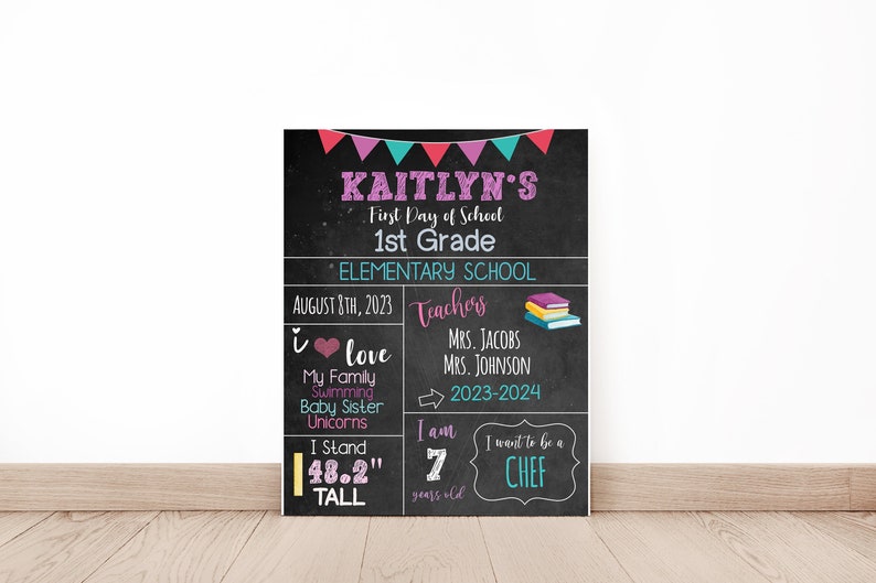 May include: A black chalkboard sign with colorful bunting at the top. The sign says "Kaitlyn's First Day of School 1st Grade * Elementary School August 8th, 2023 Teachers I love My Family Swimming Baby Sister Unicorns I Stand 48.2" tall I am 7 years old I want to be a CHEF MRS. JACOBS MRS. JOHNSON 2023-2024"