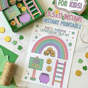 Puede incluir: Un kit de trampa para duendes arcoíris pastel con un arcoíris, un pote de oro, una escalera y un letrero que dice "FREE GOLD". El kit incluye una caja, una hoja imprimible y elementos decorativos. El texto "GREAT FOR KIDS!" también es visible.