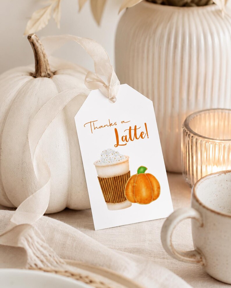 May include: A white tag with the text "Thanks a Latte!" features a watercolor illustration of a latte and a pumpkin. A white pumpkin and a ceramic mug are in the background, suggesting a fall or autumn theme.