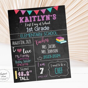 May include: A chalkboard sign with a pink, teal, and red banner at the top. The sign says "Kaitlyn's First Day of School 1st Grade Elementary School August 8th, 2023 Teachers Mrs. Jacobs Mrs. Johnson 2023-2024 I love My Family Swimming Baby Sister Unicorns I Stand 48.2" tall I am 7 years old I want to be a CHEF".