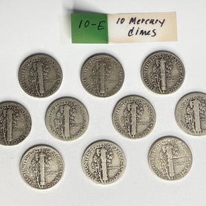 May include: Ten silver-colored United States Mercury dimes arranged in a group. Each coin features the reverse side showing a fasces and an olive branch with the text United States of America and One Dime. A paper label reads 10-E 10 Mercury dimes.