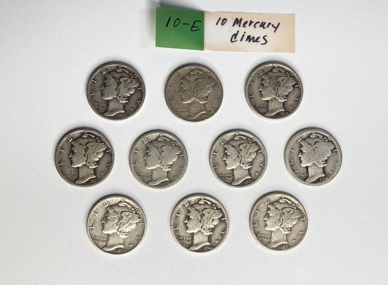 May include: Ten silver Mercury dimes arranged in three rows. Each coin features the profile of Liberty wearing a winged cap, with the text 10-E 10 Mercury dimes written on a small green and white paper tag positioned above the coins.