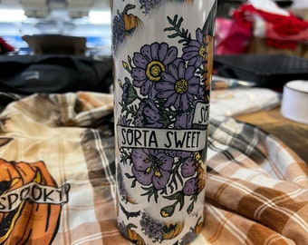 May include: A white stainless steel tumbler with a Halloween-themed design. The tumbler features purple flowers, bats, and pumpkins with the text "Sorta Sweet".