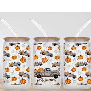 May include: Three clear glass tumblers with bamboo lids and clear straws. Each tumbler features a white background with a repeating pattern of orange pumpkins and gray pickup trucks carrying pumpkins. The middle tumbler has the text "fall junkie" printed on the bottom.