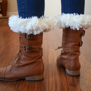 May include: Brown leather boots with white faux fur cuffs. The boots have buckles and laces.