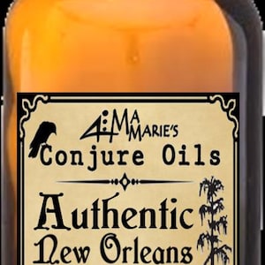 May include: A brown glass bottle with a black cap, labeled "Aima Marie's Conjure Oils." The label features text reading "Authentic New Orleans Van Van" and "Deep Down South Louisiana," along with a crow illustration and a cypress tree.