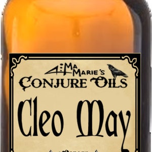 May include: A brown glass bottle with a black cap and a label that reads "Aunt Marie's Conjure Oils Cleo May 1 ounce Deep Down South Louisiana".