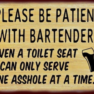 May include: A wooden sign with the text "PLEASE BE PATIENT WITH BARTENDER! EVEN A TOILET SEAT CAN ONLY SERVE ONE ASSHOLE AT A TIME." The sign has a black silhouette of a beer glass.