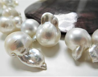 May include: A strand of white baroque pearls with an iridescent sheen. The pearls are irregular in shape and have a smooth, polished surface.