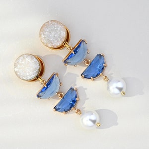 Elegantes dilatadores de oreja con cristal azul y perlas, ideales para bodas y graduaciones. Disponibles en tamaños de 8g, 6g, 4g, 2g, 0g, 00g, 1/2, 9/16, 5/8, 11/16, 3/4 y 1 pulgada.