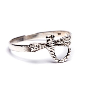 May include: A silver ring featuring a dragonfly design. The dragonfly is detailed with wings and a body.