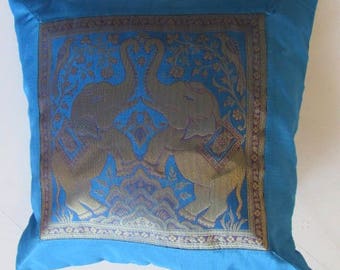 May include: Blue throw pillow with a gold embroidered design of two elephants in a floral pattern.