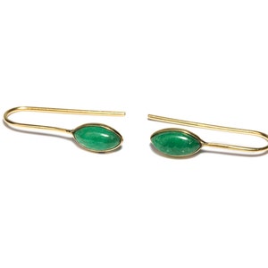 May include: A pair of gold earrings with green gemstone accents. The earrings are simple and elegant, with a delicate wire design.