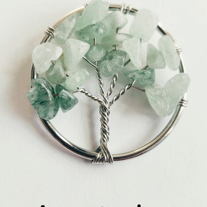 Puede incluir: Un colgante de &aacute;rbol de la vida envuelto en alambre plateado con piedras de aventurina verde.