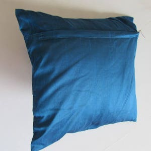 May include: A blue pillow with a zipper closure. The pillow is made of a soft, smooth fabric.