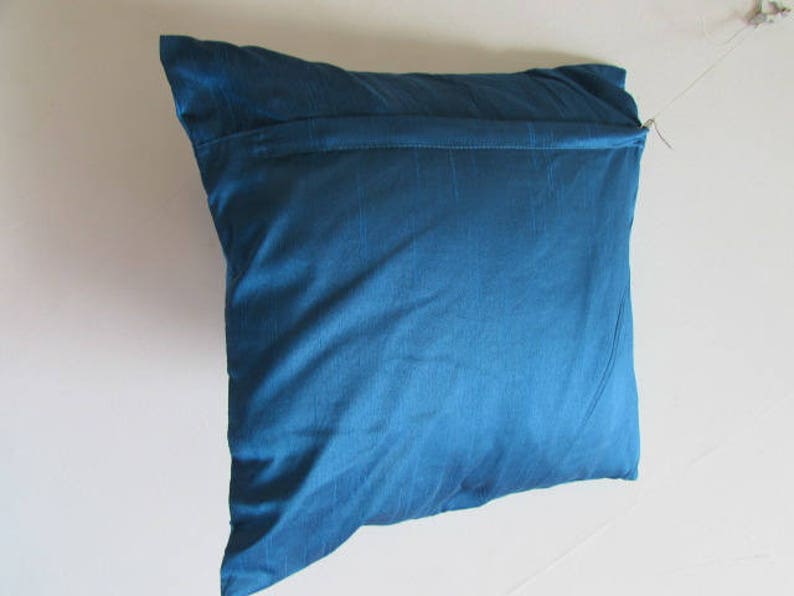 May include: A blue pillow with a zipper closure. The pillow is made of a soft, smooth fabric.
