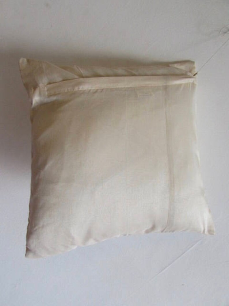 May include: A plain white pillow with a zipper closure. The pillow is made of a soft, silky fabric.