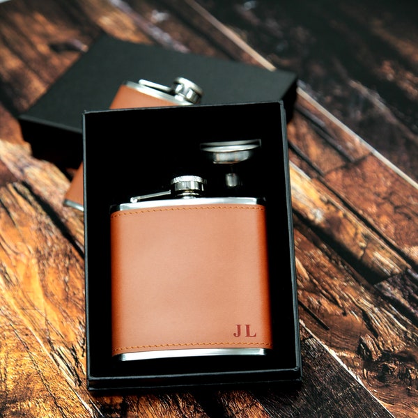 May include: A brown leather-wrapped flask with a silver lid and a silver funnel. The flask has the initials "JL" engraved on the front.