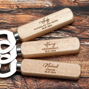 May include: Three wooden bottle openers with engraved names and titles, including "Andy Father of the Bride 28.07.2024", "Harry Groomsman 28.07.2024", and "Michael Groom 28.07.2024".