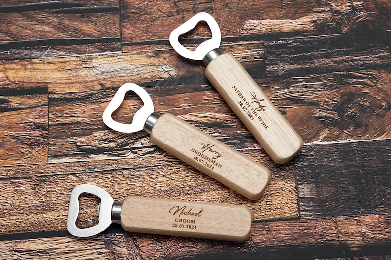 May include: Three wooden bottle openers with engraved text. The top opener says "Harry Father of the Bride 28.07.2024". The middle opener says "Harry Groomsman 28.07.2024". The bottom opener says "Michael Groom 28.07.2024".