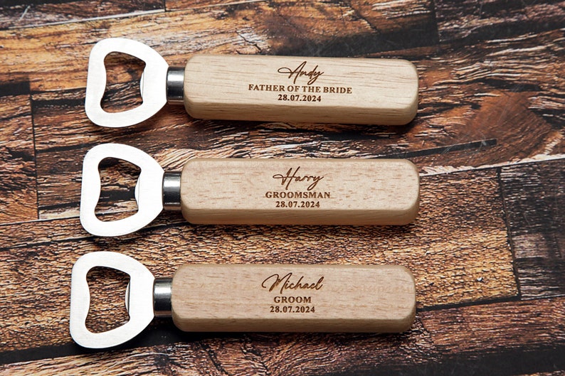 May include: Three wooden bottle openers with engraved text. The top opener says "Andy Father of the Bride 28.07.2024". The middle opener says "Harry Groomsman 28.07.2024". The bottom opener says "Michael Groom 28.07.2024".