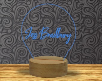 May include: A wooden base with a light bulb shaped neon sign that says "Jess Bradbury".