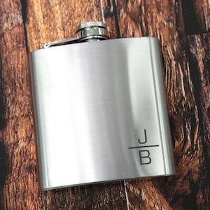 May include: A silver flask with a screw-on cap and a personalised inscription that reads "J/B".