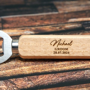 May include: Wooden bottle opener with a metal opener and a personalized inscription that reads "Michael Groom 28.07.2024".