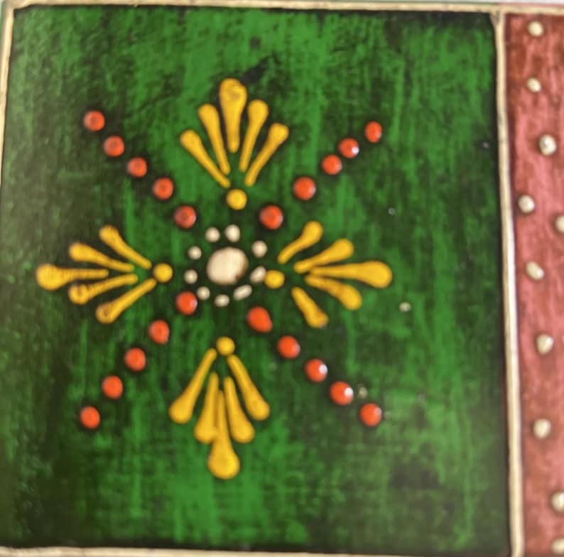 K&ouml;nnte beinhalten: Eine quadratische Keramikfliese mit tiefgr&uuml;nem Hintergrund und einem zentralen gelb-wei&szlig;en Blumenmotiv. Das Design umfasst strahlenf&ouml;rmige orangefarbene Punkte und gelbe Bl&uuml;tenblattformen. Ein vertikaler Rand rechts ist rosa mit wei&szlig;en Punkten.