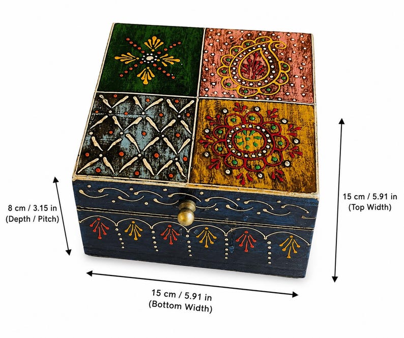 K&ouml;nnte beinhalten: Eine quadratische Holzschatulle mit Klappdeckel, die vier verschiedene bemalte Felder in Gr&uuml;n, Rosa, Blau und Gelb mit komplexen Blumen- und Geometriemustern aufweist. Die dunkelblaue Vorderseite hat einen Messingknopf und misst 15 cm Breite, 15 cm Tiefe und 8 cm H&ouml;he.