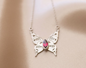 May include: A silver butterfly necklace with a red gemstone pendant.