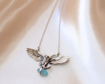 May include: Silver owl necklace with a blue gemstone pendant. The owl is depicted with its wings spread and has detailed features.