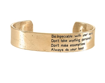 May include: Gold-toned metal bracelet with an inspirational quote engraved on the band: "Be impeccable with your word. Don't take anything personally. Don't make assumptions. Always do your best."