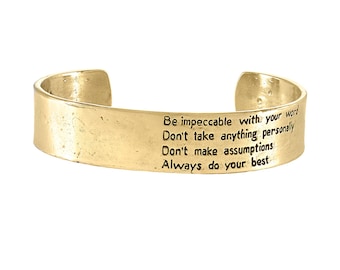 May include: Gold-toned metal bracelet with an inspirational quote engraved on the band: "Be impeccable with your word. Don't take anything personally. Don't make assumptions. Always do your best."