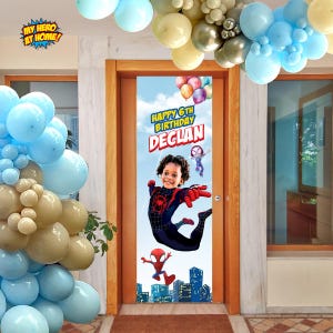 K&ouml;nnte beinhalten: Ein vertikales, rechteckiges T&uuml;rbanner zum Geburtstag mit blauem Himmelshintergrund und einer Stadtsilhouette am unteren Rand. Das Banner zeigt den Text Happy 6th Birthday Declan, ein Kind im Spinnenkost&uuml;m und Zeichentrickfiguren.
