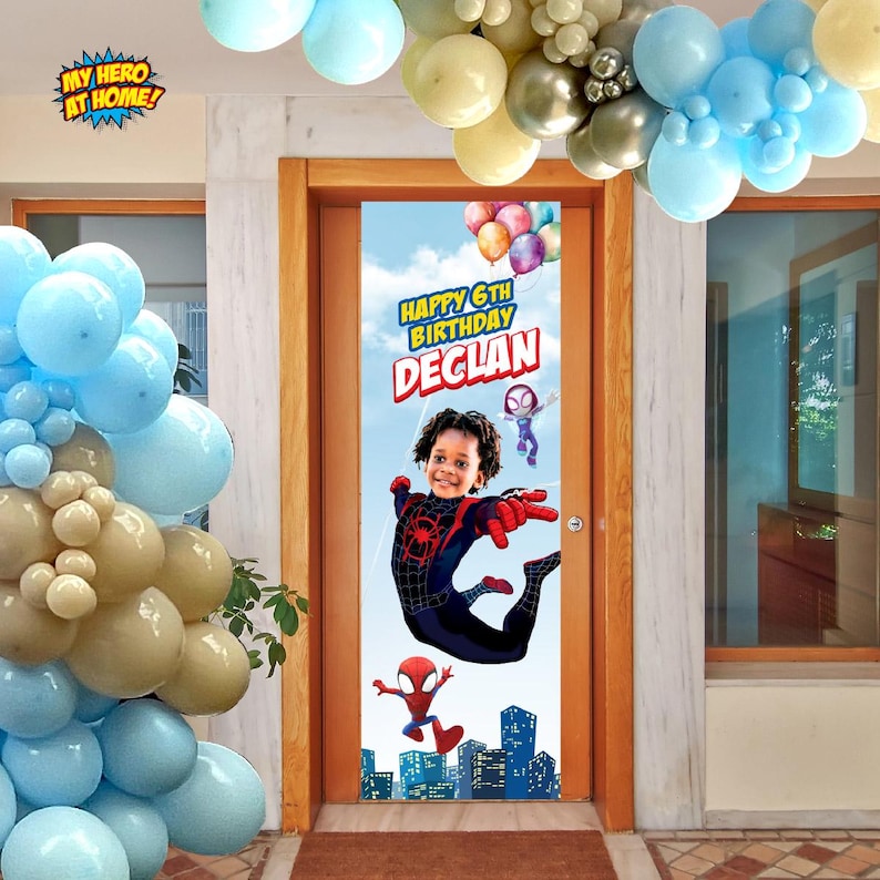 K&ouml;nnte beinhalten: Ein vertikales, rechteckiges T&uuml;rbanner zum Geburtstag mit blauem Himmelshintergrund und einer Stadtsilhouette am unteren Rand. Das Banner zeigt den Text Happy 6th Birthday Declan, ein Kind im Spinnenkost&uuml;m und Zeichentrickfiguren.