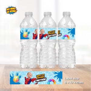 Peut inclure: Trois bouteilles d'eau en plastique transparent avec des &eacute;tiquettes personnalis&eacute;es. Les &eacute;tiquettes pr&eacute;sentent un enfant en costume de super-h&eacute;ros, un ballon de plage color&eacute; et le texte "HAPPY 5TH BIRTHDAY MATTHEW". La taille de l'&eacute;tiquette est de 20 x 25 cm.
